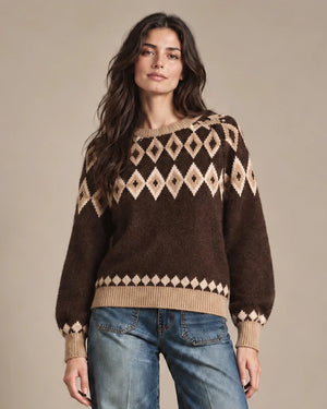 Close-up of Odessa brown sweater worn untucked, showing the diamond-knit pattern and beige ribbed hem.