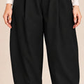 Front detail of black Queen Nero barrel-leg trousers showing the button-detail waistband, front pleats and pleated ankle hems.