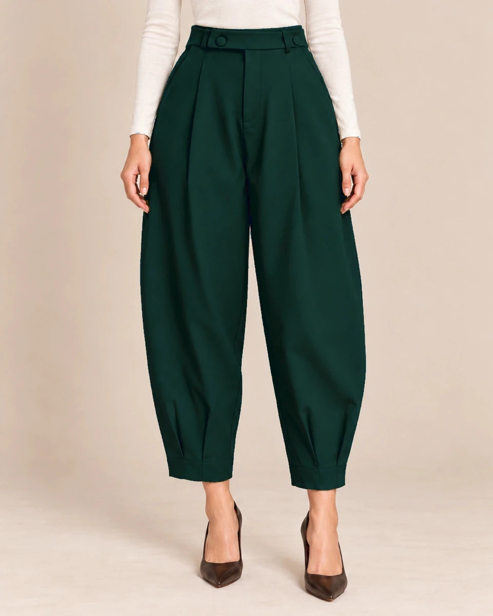 Front detail of bottle green Queen barrel-leg trousers showing the button-detail waistband, front pleats and pleated ankle hems.
