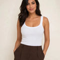 White ribbed tank top tucked into dark brown trousers, front view