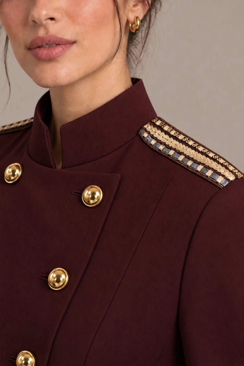 Close-up of the burgundy blazer's stand collar, gold-tone buttons and decorative shoulder trim.