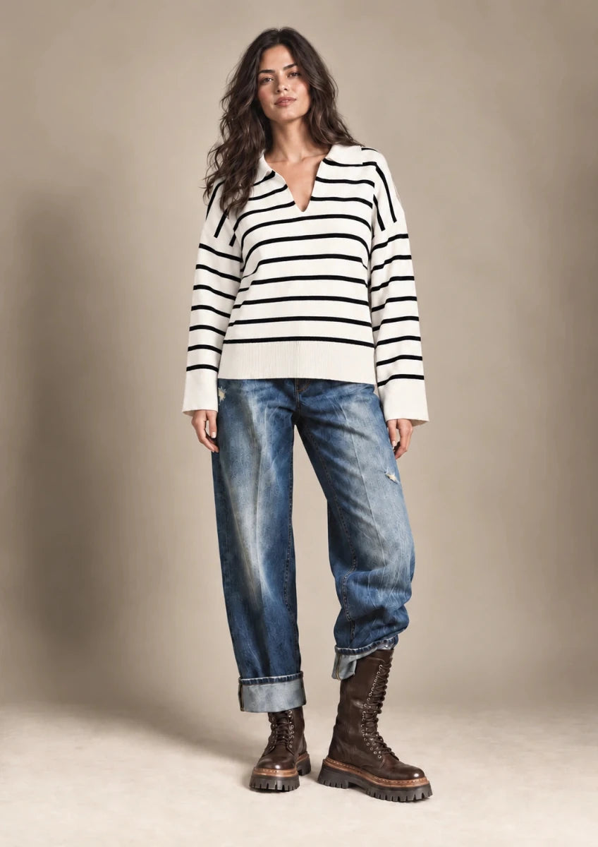 Full-length front view of Rossana cream-and-black striped sweater worn untucked with blue jeans.