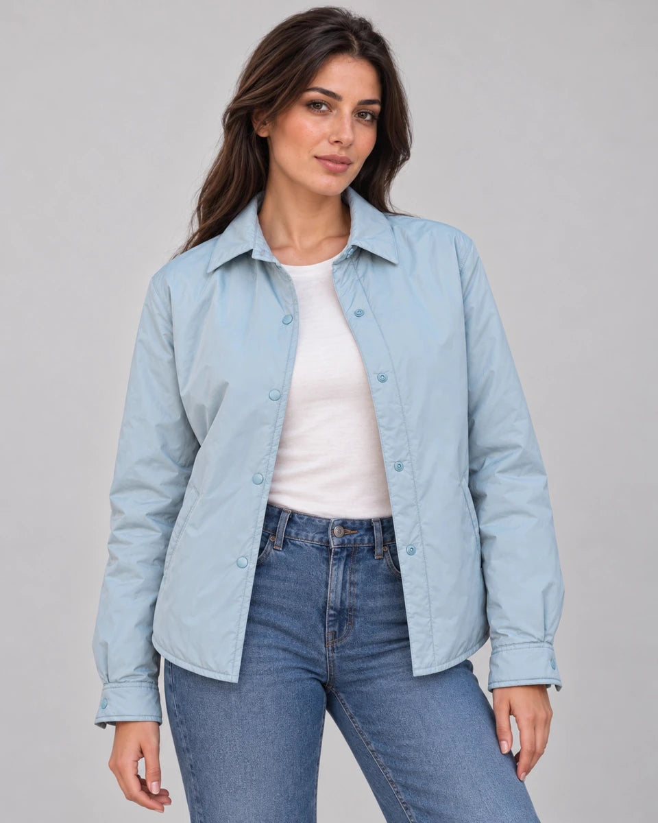 Front view of the pale blue Sky Mist Windbreaker Jacket worn open over a white top and jeans, showing the collar and snap fastenings.