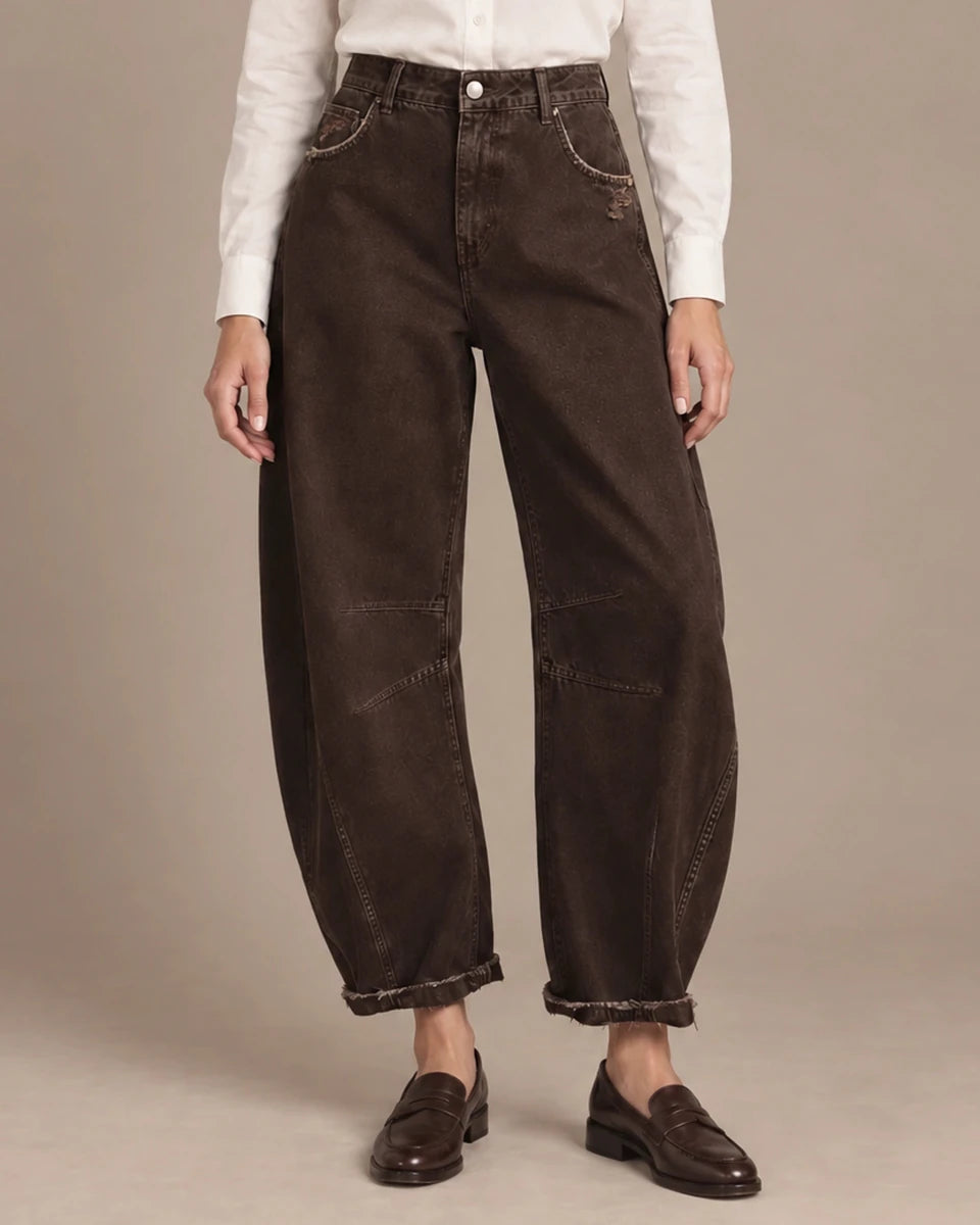 Front view of brown barrel-leg trousers showing panel seams, distressed details and turned-up hems.