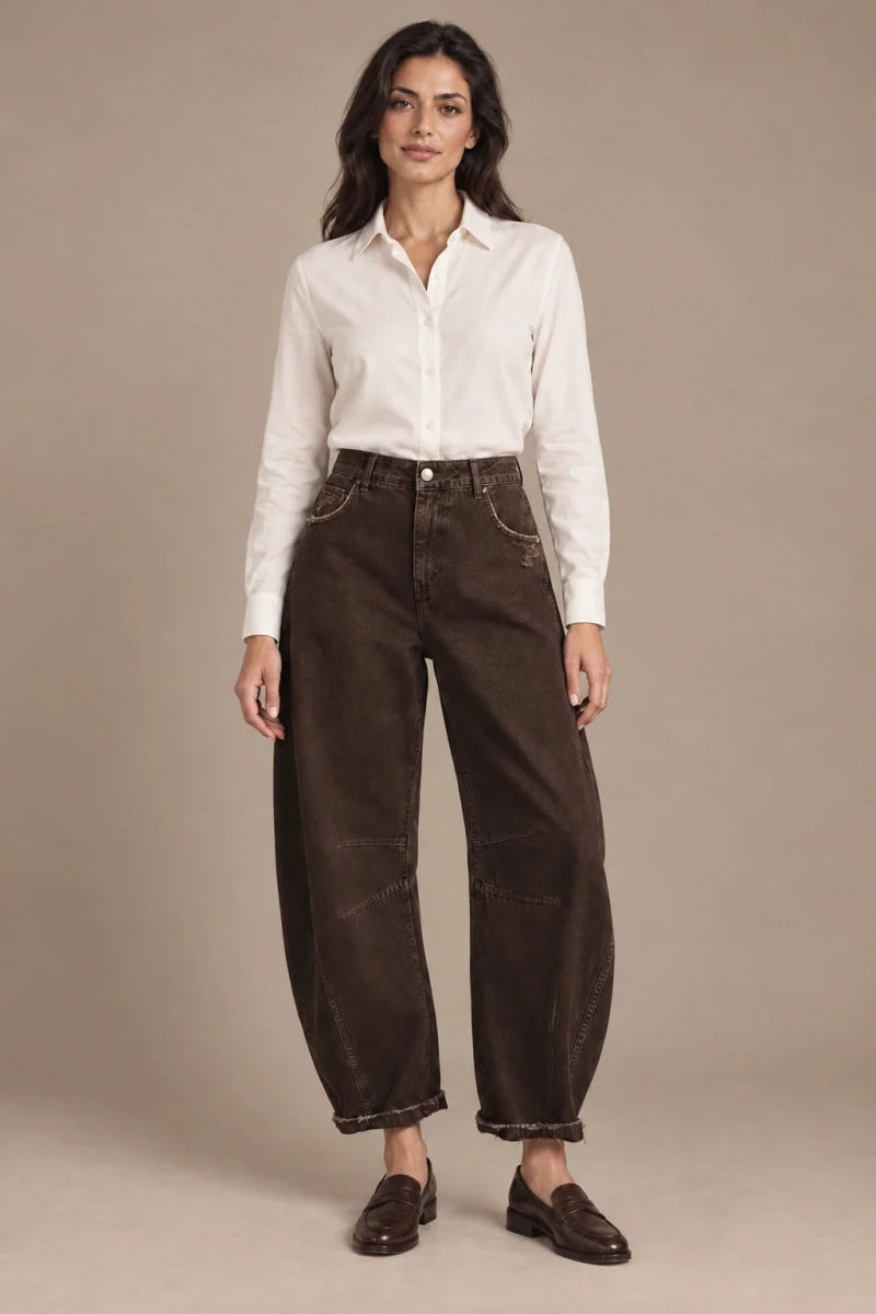 Full-length view of a model wearing brown barrel-leg trousers with a white shirt and brown loafers.
