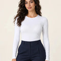 White stretch-cotton crew-neck long-sleeve top tucked into navy tailored trousers, front view