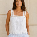 Front flat-lay view of the ELLY white camisole top with floral eyelet embroidery, wide lace straps, a square neckline, and a scalloped floral hem.