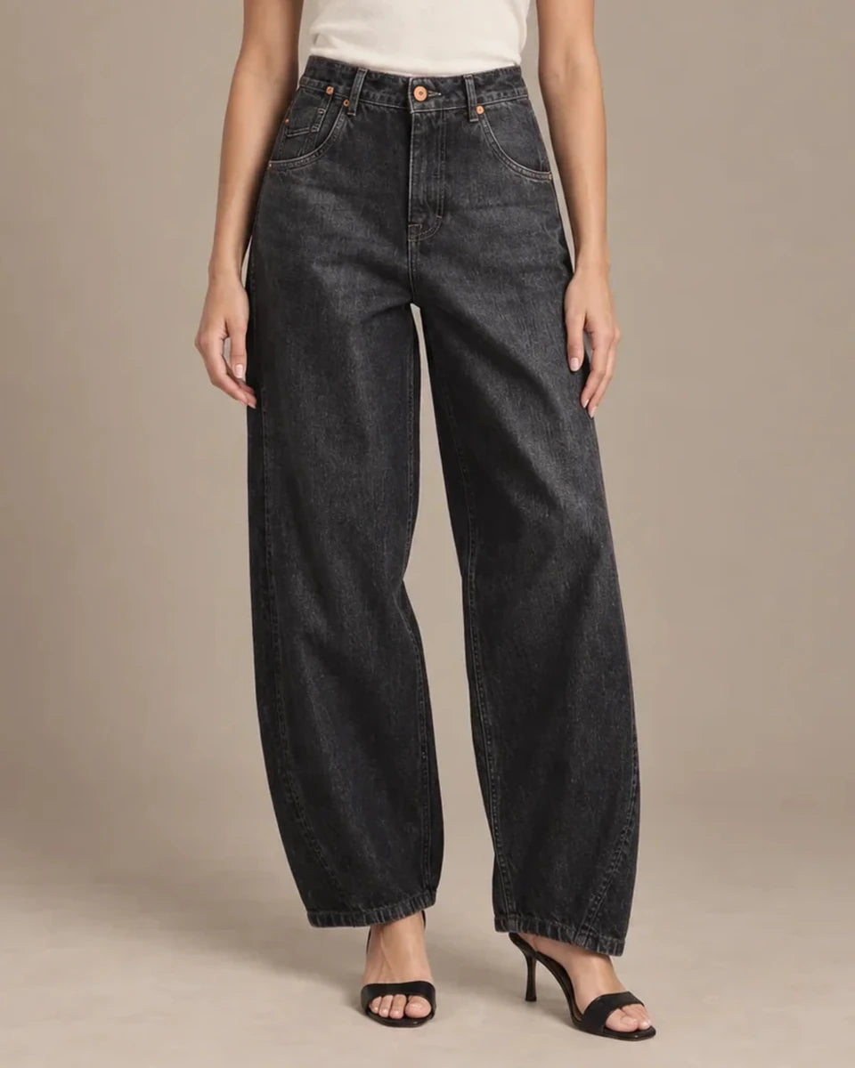 Front detail of the dark-wash Zaira barrel-leg jeans, showing the button waistband, curved front pockets and shaped legs.